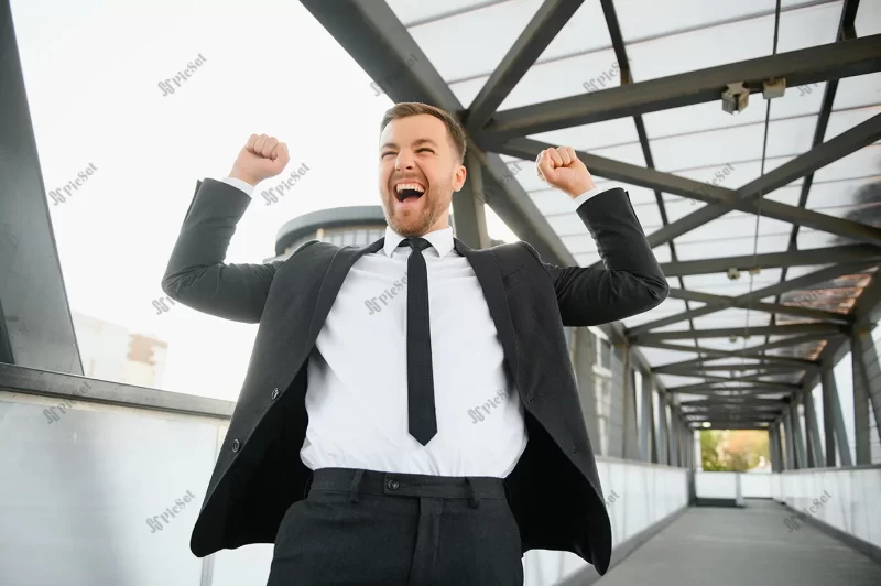 successful businessman celebrating his victory with arms up cityscape background / مرد موفقی که پیروزی خود را با پس‌ زمینه‌ی منظره‌ی شهری جشن می‌گیرد