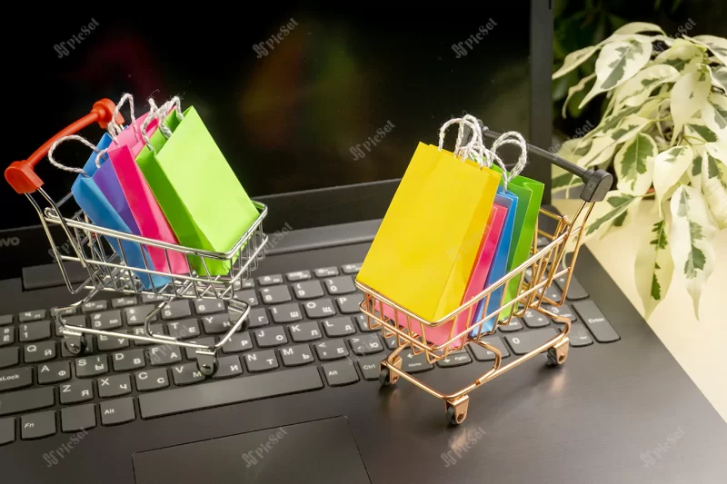 online shopping concept little deliver boxes smartphone shopping bags shopping bascket stand laptop copy space / مفهوم خرید آنلاین جعبه های تحویل کوچک سبد خرید کارت اعتباری اسکناس دلار روی لپ تاپ