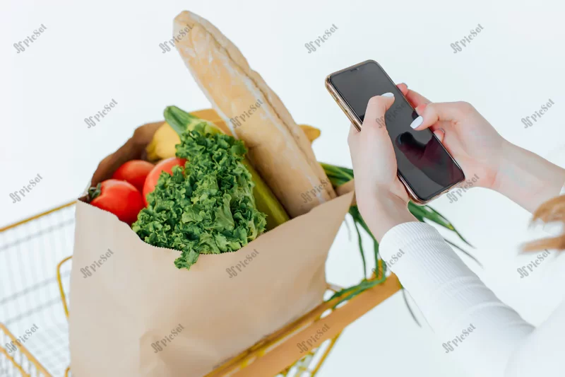 supermarket woman uses smartphone leans shopping cart / زن در سوپرمارکت با سبد خرید و گوشی هوشمند موبایل