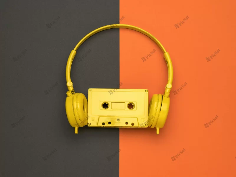 yellow cassette with magnetic tape yellow headphones orange black background color trend flat lay / نوار کاست زرد با هدفون زرد پس زمینه نارنجی و سیاه
